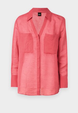 Koraalkleurig linnen overhemd met een V-hals, knoopsluiting en twee borstzakken. Lange mouwen met knoopmanchetten. Lichtgewicht, ademende stof.