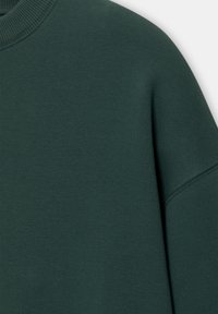 Green sweatshirt with a crew neck, made of textured fabric. Features a ribbed neck and slightly dropped shoulders for a relaxed fit.