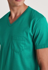 Teal V-hals T-shirt van zacht materiaal met korte mouwen, voorzien van een zak aan de linkerkant van de borst en een subtiele textuur. Regular fit met een casual ontwerp.