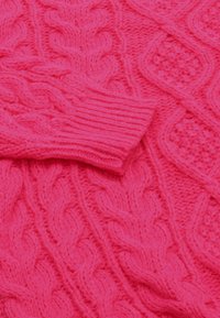 Maglione rosa lavorato a maglia con un intricato motivo a cable e polsini a costine. Realizzato in morbido e soffice filato, mette in risalto dettagli testurizzati.