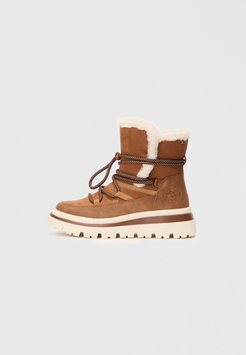 Bottines en suède marron avec doublure en fourrure, semelle épaisse beige et lacets marron. Présente un logo sur le côté.