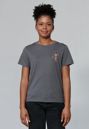 T-shirt en coton gris à manches courtes, ornée d'un petit graphique coloré d'une danseuse hula sur la zone gauche de la poitrine.