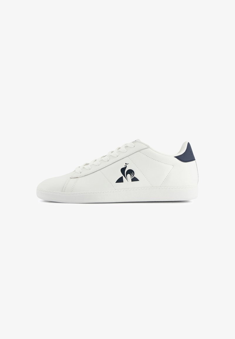 White leather sneaker with navy accents, round toe, flat sole, and logo detail on the side. Features classic lace-up closure.