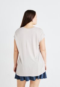 Helles graues Kurzarm-Jersey-T-Shirt mit lockerer Passform. Glatte Textur, runder Ausschnitt. Kombiniert mit einem Jeansrock.