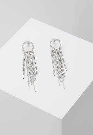 Des boucles d'oreilles en argent présentent une attache circulaire avec des chaînes de petits bijoux en rhinestones, créant un effet de frange superposée.