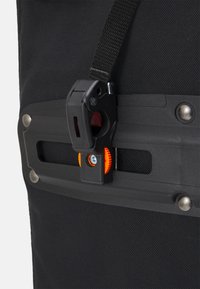 Bolsa de tela negra con cierre de hebilla de plástico, presentando una rueda de ajuste naranja y acentos metálicos. Superficie texturizada para mayor durabilidad.