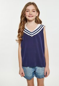Donkerblauwe mouwloze top met een V-hals en witte kraag met drie horizontale strepen; gecombineerd met denim shorts. Gladde textuur.