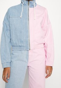 Džínová bunda s designem půleným na modrou a růžovou polovinu, s vysokým límcem, zapínáním na zip a elastickými manžetami a lemem.