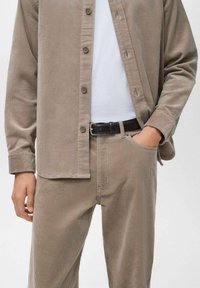 Conjunto de camisa y pantalones de pana en color topo, que incluye una camisa abotonada con acabado texturizado y un cinturón a juego.