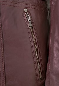 Burgunderfarbene Lederjacke mit einem silbernen Reißverschlussfach, dekorativer Naht und glatter Textur. Kompakte und taillierte Form.