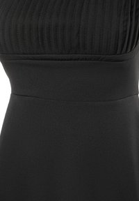 Robe noire avec taille cintrée et texture côtelée sur la partie supérieure au-dessus de la taille.
