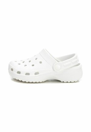 Zapato tipo zueco blanco con puntas redondeadas, múltiples agujeros de ventilación, una correa trasera y suela texturizada para agarre. Fabricado con material ligero.
