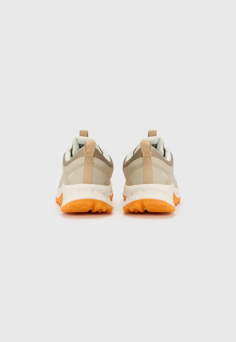 Zapatillas deportivas beige con un upper texturizado, suela naranja y tiradores en el talón. Diseñadas para la comodidad y la estabilidad durante el movimiento.