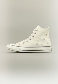 Λευκό sneaker ψηλού τύπου με λευκά κορδόνια και μικρά κεντητά λουλούδια μαργαρίτας στο πλάι, μαύρη ρίγα στη σόλα.