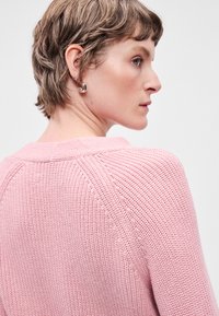 Ροζ πλεκτό πουλόβερ με υφή σχεδίου και φαρδύ λαιμόκοψη, με διακριτές ραφές και χαλαρή εφαρμογή.
