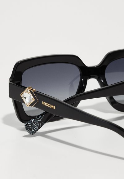 Mustad mustad prillid gradient läätsedega, millel on kuldne teemantaktsent templis. Relvade tekstureeritud mustriga sisepind.