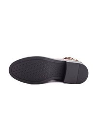 Suela de un zapato de vestir de cuero marrón con agarradera de goma negra y tacón texturizado, mostrado sobre un fondo blanco.