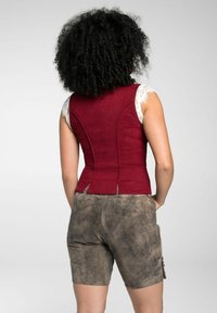 Burgunderfarbener, taillierter Weste mit Spitze und ärmellosem Design, kombiniert mit strukturierten braunen Shorts mit seitlichen Knöpfen und einer lockeren Passform.