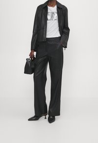 Czarna skórzana kurtka, biała koszulka z cekinowym wzorem, czarne skórzane szerokie spodnie i buty z wydłużonym czubkiem. Dodatki to mała czarna torebka.