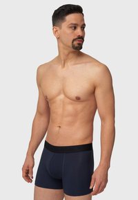 Mørkeblå boxershorts med en sort elastisk midjebånd med hævet skrift. Fremstillet af et glat, strækbart stof for komfort.