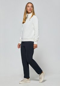 Witte fleece half-zip sweatshirt, marineblauwe broek en lichte sneakers. Glad textuur, relaxte pasvorm en eenvoudig ontwerp met minimale details.