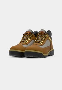 Brown hiking shoes with gray accents, gold hooks, and multicolored laces. Features a rugged sole and smooth leather upper with textured fabric.