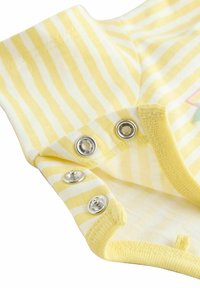 Vêtement de bébé jaune et blanc à rayures avec trois boutons-pression métalliques partiellement ouverts sur les bords du tissu.