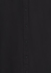 Posnetek črne tkanine središča s šestimi črnimi gumbi v vertikalnem zaporedju.