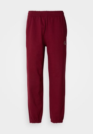 Bordeaux sweatpants met een elastische tailleband en enkelmanchetten. Heeft een klein geborduurd logo op het linkerbeen. Gemaakt van een zachte stof.