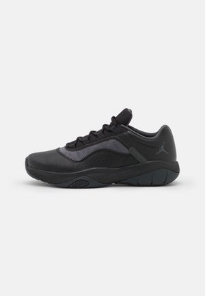 Schwarzer flacher Sportschuh mit Mesh-Einsatz, Schnürverschluss und Jumpman-Logo an der Ferse vor weißem Hintergrund.