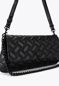 Borsa a spalla in pelle nera con design trapuntato, tracolla in catena e pelle, e un dettaglio decorativo in metallo nero sulla parte anteriore.