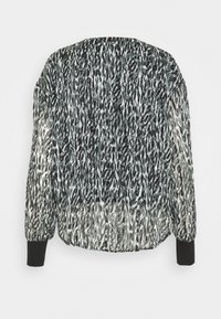 Chaqueta bomber de patrón en blanco y negro con tejido texturizado, puños acanalados y un ajuste relajado, mostrando un diseño fluido y detalles impresos.