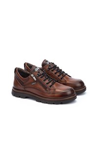 Chaussures en cuir marron avec un bout arrondi, un design à lacets, une fermeture éclair sur le côté et une semelle en caoutchouc texturée. Présentent des coutures visibles et des accents de logo.
