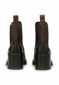 Smeđe kožne gležnjače s okruglim vrhom, elastičnim bočnim panelima i debelom blok petom, ukrašene šivanjem na gornjem dijelu.