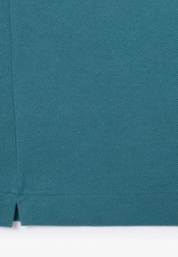 Teal-kankainen kangas, jossa on rakenteellinen kudos, ja alareunassa on jaettu helma-yksityiskohta, joka lisää suunnittelu-innostusta.