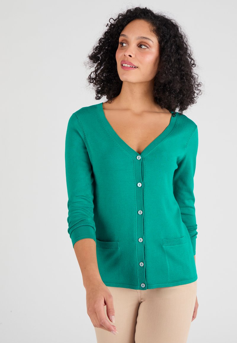 Cardigan verde con scollo a V, maniche lunghe e chiusura a bottoni. Presenta due tasche frontali e una texture liscia e morbida.