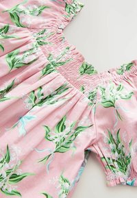 Rosa Blumenkleid mit grünen und weißen Pflanzenmustern, versehen mit gerüschten Schultern, kurzen Ärmeln und einer schwingenden A-Linie.