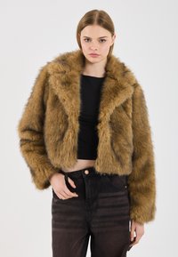 Brun faux fur cropped jakke med bred krave, lange ærmer og en blød tekstur. Kombineret med højtaljede mørke jeans.