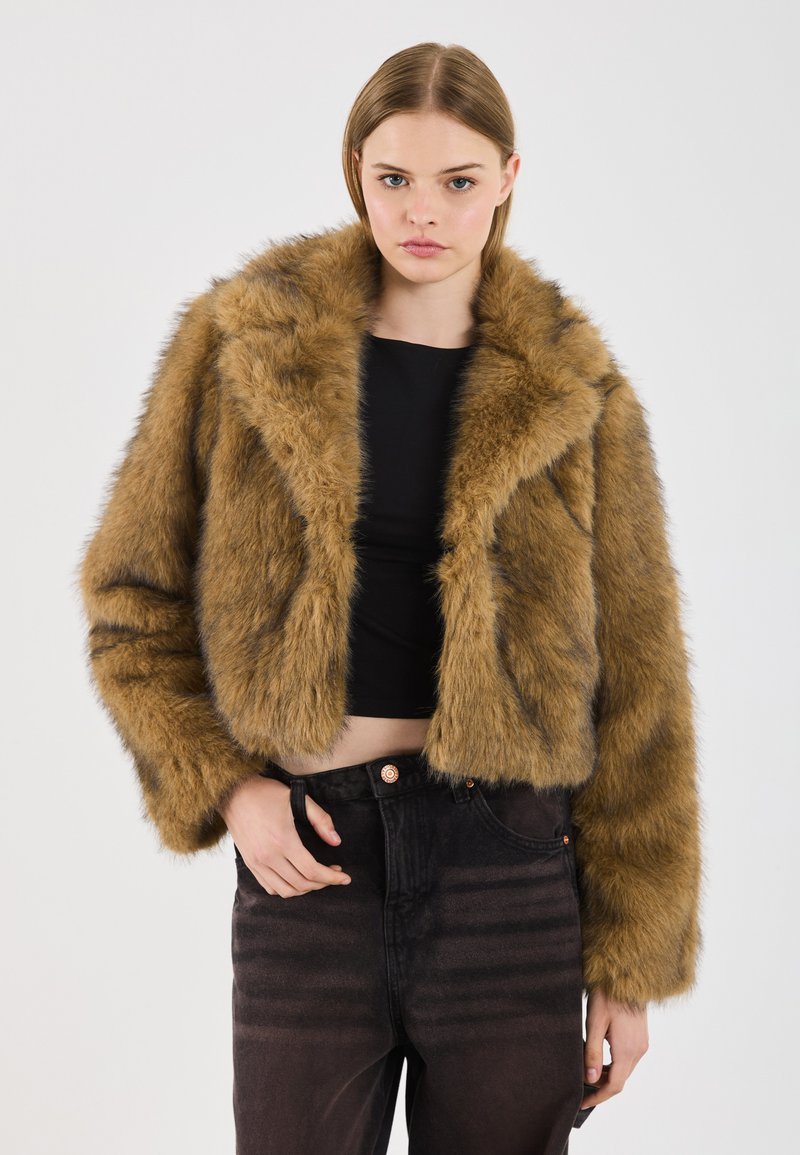 Brun faux fur cropped jakke med bred krave, lange ærmer og en blød tekstur. Kombineret med højtaljede mørke jeans.