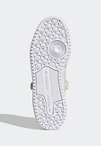 Suola di sneaker in gomma bianca con motivi circolari testurizzati e una sezione rigata. Presenta un dettaglio con scanalatura circolare e logo in rilievo.