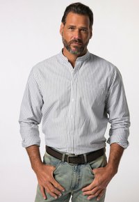 Camicia a righe in grigio chiaro e bianco. Presenta un colletto alla cinese e maniche lunghe. Indossata con jeans in denim e una cintura marrone.