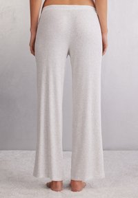 Zachte, lichtgrijze geribde loungebroek met een ontspannen pasvorm, wijde benen en een elastische tailleband. Opvallende textuur door het geribde patroon.