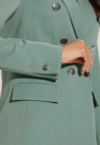 Dubbel breasted blazer in lichtgroene stof, met glanzende metallic knopen, gestructureerde schouders en zijzakken met een zachte textuur.