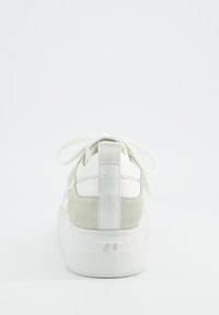 White sneaker with a suede grey heel, flat laces, and a padded collar. Features a textured back and a platform sole with logo detailing.