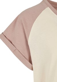 Raglan-skjorte med kort erme i lys beige kropp og støvete rosa ermer, med oppbrettede mansjetter og synlige sømdetaljer.