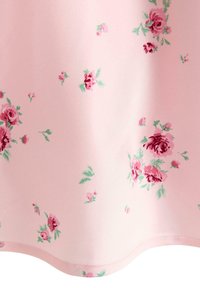 Roze stof met een zachte textuur, met een bloemenpatroon van verschillende tinten rode rozen en groene bladeren. De randen zijn glad en gebogen.