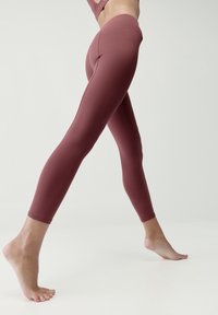 Bordové legíny vyrobené z elastického materiálu, s hladkou textúrou a priliehavým strihom, vysokým pásom a bez viditeľných švov.