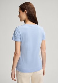 T-shirt azzurro chiaro a maniche corte realizzato in morbido cotone. Presenta un colletto rotondo e un orlo leggermente curvato. Texture liscia con dettagli di cucitura minimi.