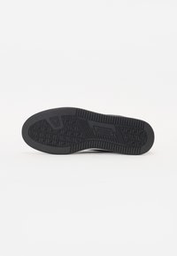 Schwarze Gummisohle mit strukturiertem Griff und geometrischen Mustern, gekennzeichnetem Branding und definierten Kanten für verbesserten Halt.