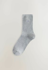 Grå ribbad strumpa med ett hjärtmönster nära toppen. Mjuk textur med en standard strumpform och förstärkt tå.